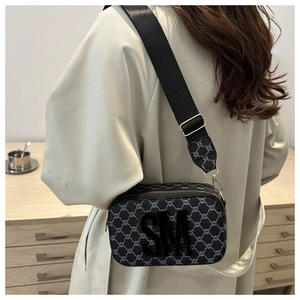 Detail of crossbody bag with black SM logo and patterned texture on wide strap
