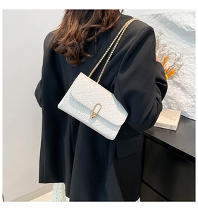 Detail of white woven texture shoulder bag with gold chain and metal buckle
