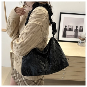 Detail of black large capacity shoulder bag featuring glossy liquid marble texture