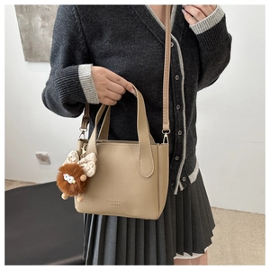 Vue détaillée du sac seau en cuir grainé kaki avec breloque peluche et logo mode