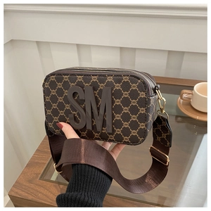 Detail of vintage crossbody bag with brown monogram pattern and golden hardware strap