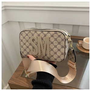 Close-up of retro crossbody bag with monogram pattern and wide nylon shoulder strap
