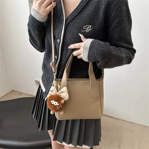 Sac seau chic en cuir beige avec breloque en peluche et bandoulière réglable pour femme