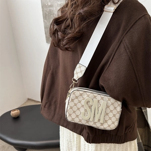 Retro cream crossbody camera bag with brown floral print and wide strap on model