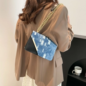 Chic patchwork shoulder bag featuring black faux leather and distressed blue denim fabric