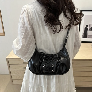 Chic black crescent underarm bag with lace-up bow design and glossy finish for women