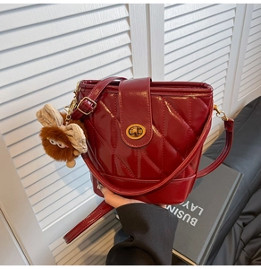 Detail of red quilted patent leather bucket bag with gold lock and plush monster charm