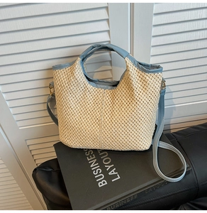 Detail showing blue leather strap and woven straw texture of a bucket tote bag