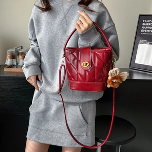 Quilted red bucket bag with gold lock and plush charm accessory for women
