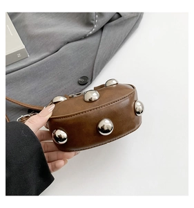 Close-up of brown leather handbag with large silver round studs on the side panel