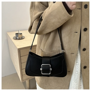 Detail of a chic black French baguette bag with a silver square buckle on the shoulder