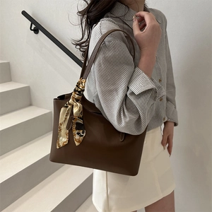 Fashionable dark brown leather tote bag with vintage patterned scarf on handle for women