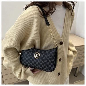 Detail of grey monogram underarm bag with gold M logo and chain strap on model