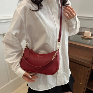 Sac hobo tendance en cuir bordeaux avec chaîne dorée pour femme porté à l'épaule