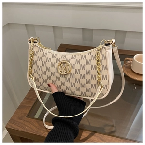 Detail shot of white shoulder bag with brown M-pattern and golden metal logo