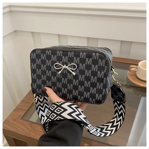 Close-up of black crossbody bag with monogram M print and textured wide shoulder strap