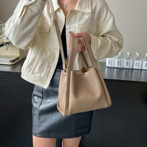 Chic beige pebbled leather bucket bag with FASHION embossment shown in a lifestyle setting