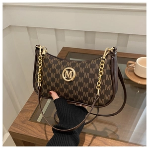 Detail of vintage brown shoulder bag with monogram texture and golden M logo hardware