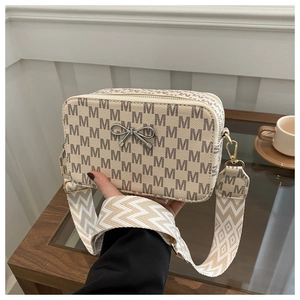 Close-up of cream square crossbody bag with letter patterns and silver bow decoration