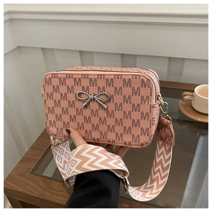 Detail of a pink crossbody bag with M-pattern, silver bow buckle, and wide woven strap