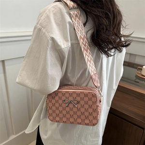 Pink monogram crossbody bag with a wide geometric shoulder strap and silver bow
