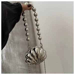 Macro detail of silver shell-shaped evening clutch with glossy metallic mirror finish