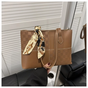 Detail of caramel brown tote bag with checkerboard embossing and silk scarf handle
