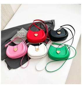 Close-up of heart-shaped gold metal buckles on colorful PU leather crossbody bags