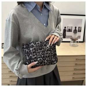 Detailed close-up of quilted leopard print clutch bag with grey fabric texture