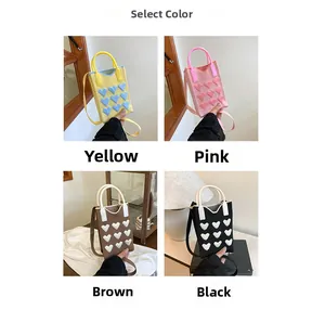 Detail view of mini knitted heart bags in four colors yellow pink coffee and black