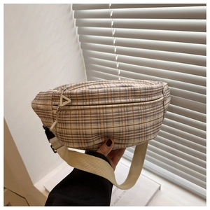 Vue détaillée d'un sac bandoulière à carreaux avec des tirettes triangulaires.