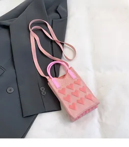 Detailed view of pink knitted mini bag with 3D heart patterns and tubular handles