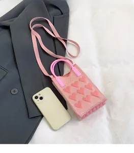 Mini pink knitted phone bag featuring heart patterns with resin handle and shoulder strap