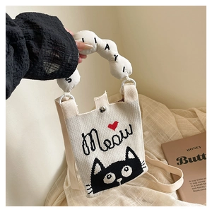 Detail of cute knitted mini phone bag with black cat embroidery and soft bubble handle