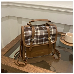 Détail du sac à dos rétro à carreaux avec logo MANIXUYI sur une table en bois