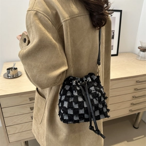 Retro black and white checkered bucket bag with drawstring closure worn as a crossbody