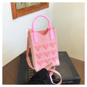 Detailed knit texture of a pink heart-pattern crossbody bag with sturdy top handle