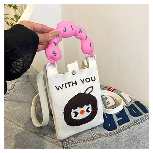 Detail of knitted mini crossbody bag featuring a cute cartoon bird and pink bubble handle