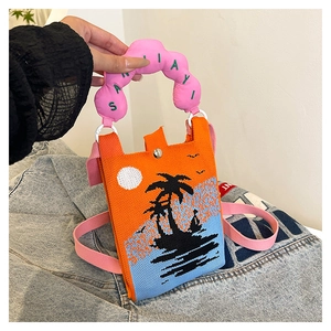 Detail of knitted mini crossbody bag with tropical sunset pattern and cloud handle