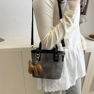 Grey canvas bucket tote bag with leather dog charm and adjustable black shoulder strap
