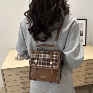 Sac à dos rétro à carreaux avec garniture en cuir marron dans un décor intérieur minimal