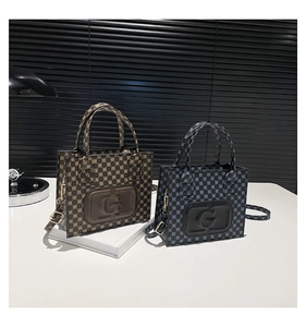 Macro shot of stylish tote bags with embossed G logo and detachable metal chain straps