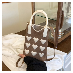 Detail of brown knitted mini crossbody bag featuring nine white 3D heart patterns