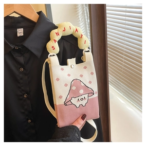 Detail of pink knitted mini crossbody bag featuring mushroom embroidery and yellow handle