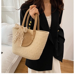 Close-up of the textured straw weave and elegant lace bow detail on a beach tote bag