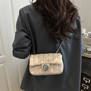 Elegant beige quilted crossbody bag with metal chain strap and twist lock on a model
