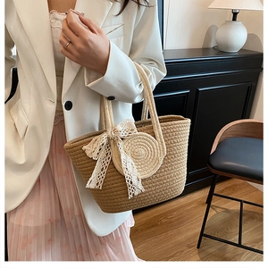 Detail of hand-woven straw tote bag with white lace bow and round decorative accents