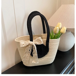 Close-up of the hand-woven texture and black lace bow detail on the summer straw tote bag