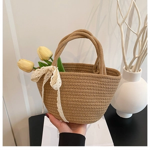 Détail du sac cabas en paille tissé main avec nœud en dentelle et accents floraux