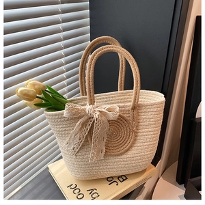 Close-up of woven straw tote bag featuring a beige lace bow and realistic tulips